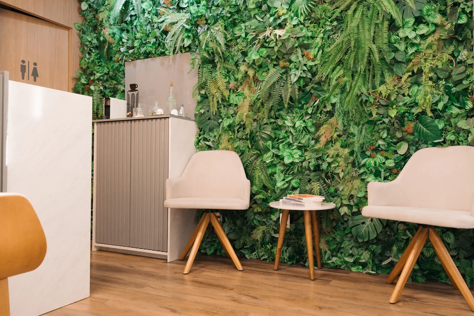 Recepção com jardim vertical, poltronas claras e balcão de mármore